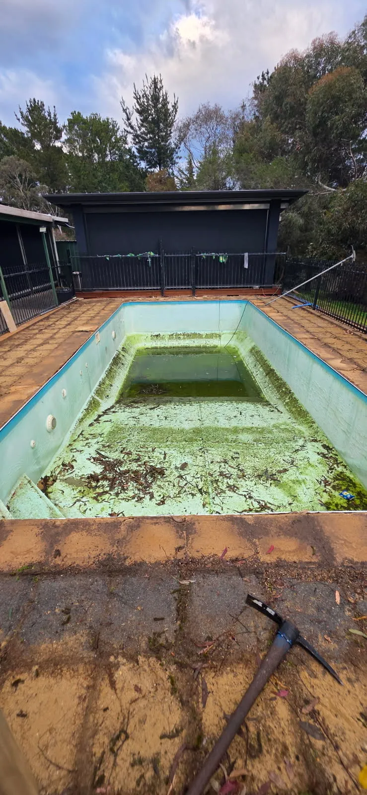 Neglected pool before renovation at Mosquito Hill showing algae buildup, deteriorated surface, and worn brick paving