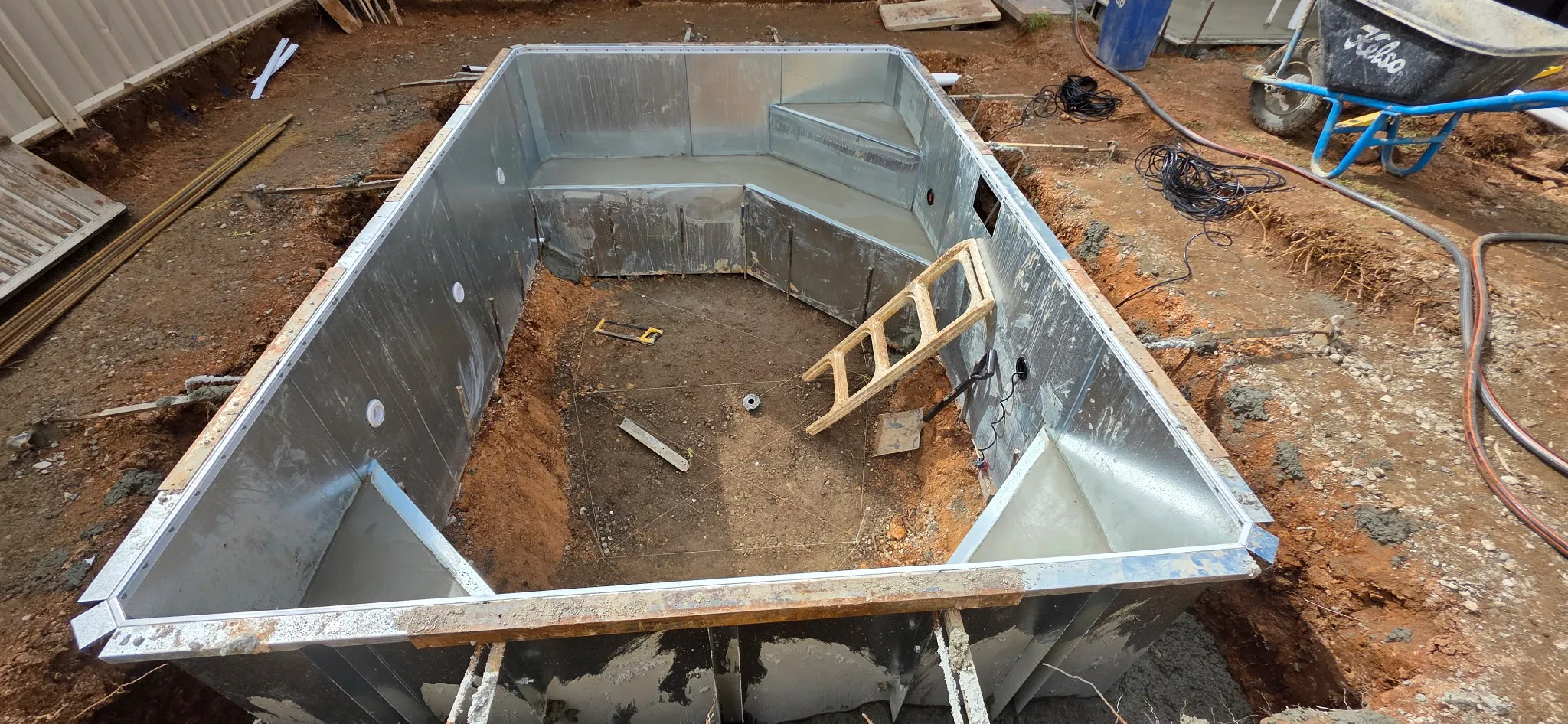 Steel pool frame in ground with lower bond beam and step entry concreted at Manningham plunge pool build