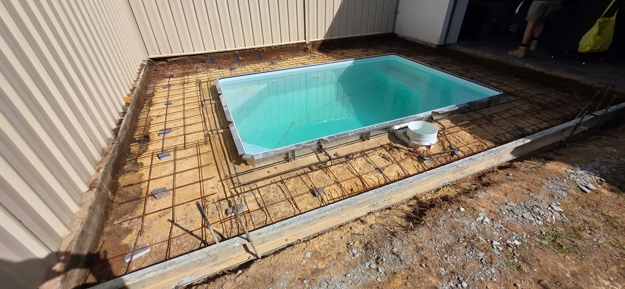 Reinforcing mesh laid around filled plunge pool with thickened edge formwork for glass fencing spigots