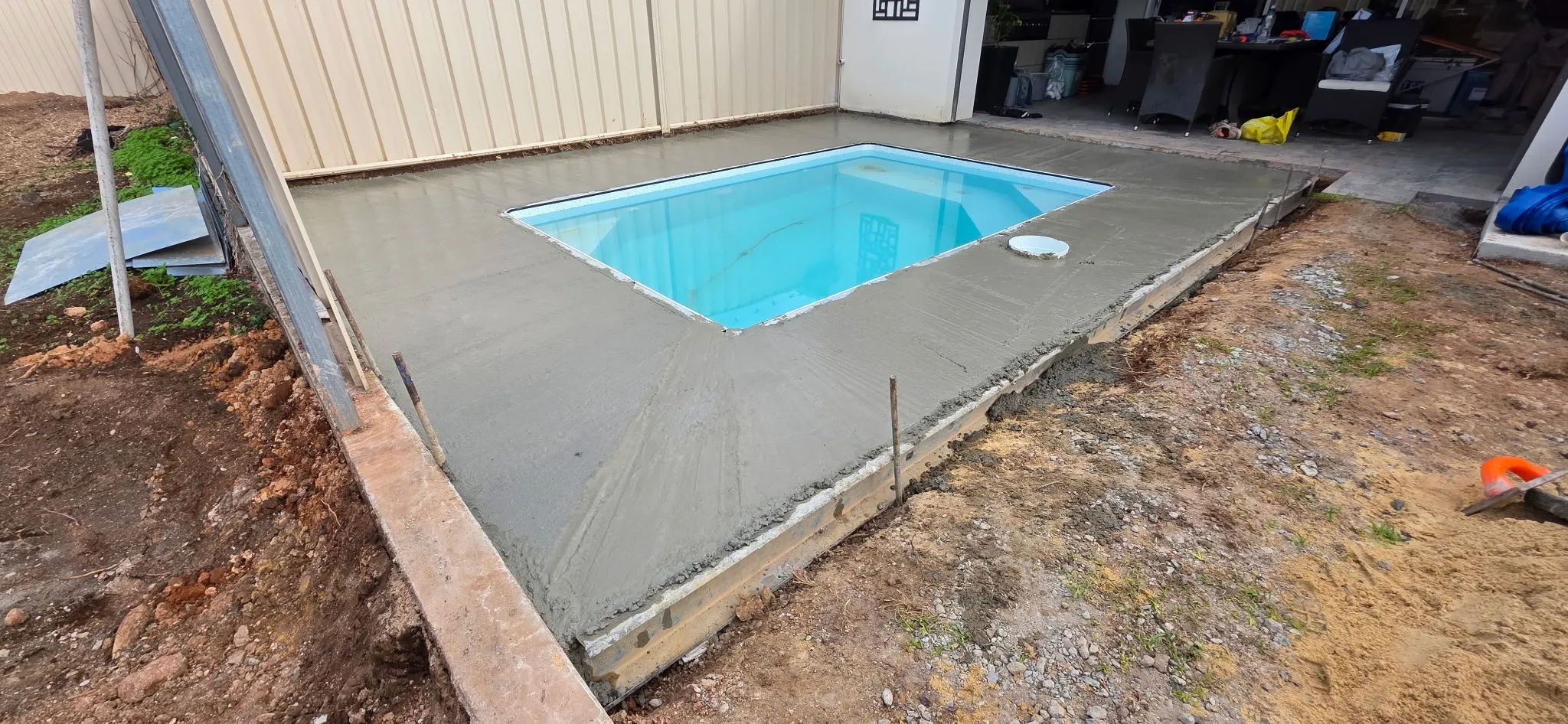 Fresh concrete poured around plunge pool with formwork and thickened perimeter edge visible