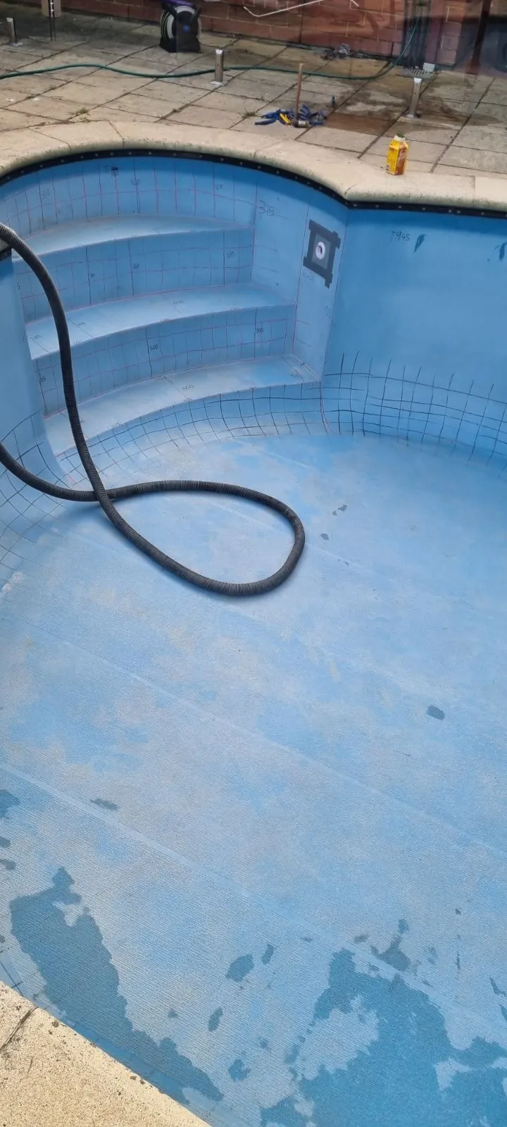Close-up of fibreglass pool step entry and floor before renovation showing measurement markings and peeling surface