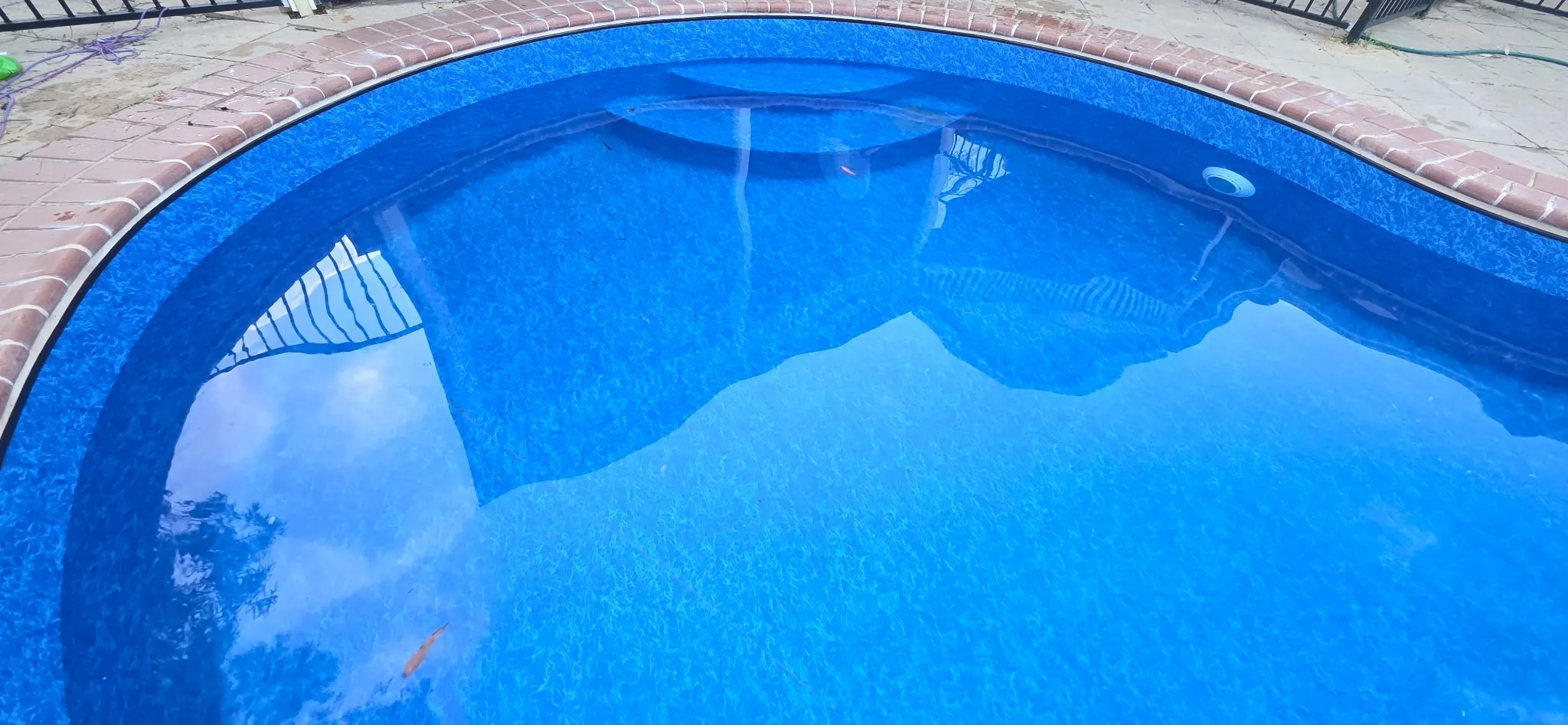 Deep end detail of renovated Coromandel Valley pool with vibrant Maui liner and sky reflections on water surface
