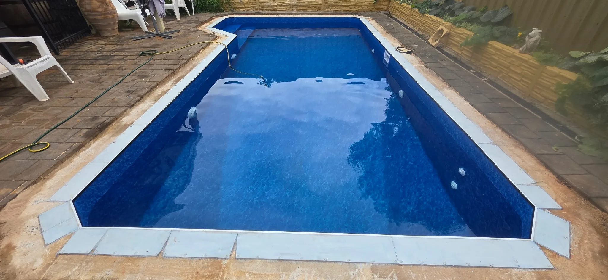 Completed pool renovation at Andrews Farm showing Aqualux Maui liner filled with step entry and paver surround