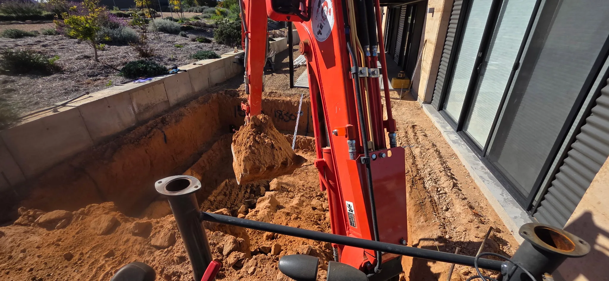 Excavator digging pool hole at Port Broughton with rural Spencer Gulf landscape beyond