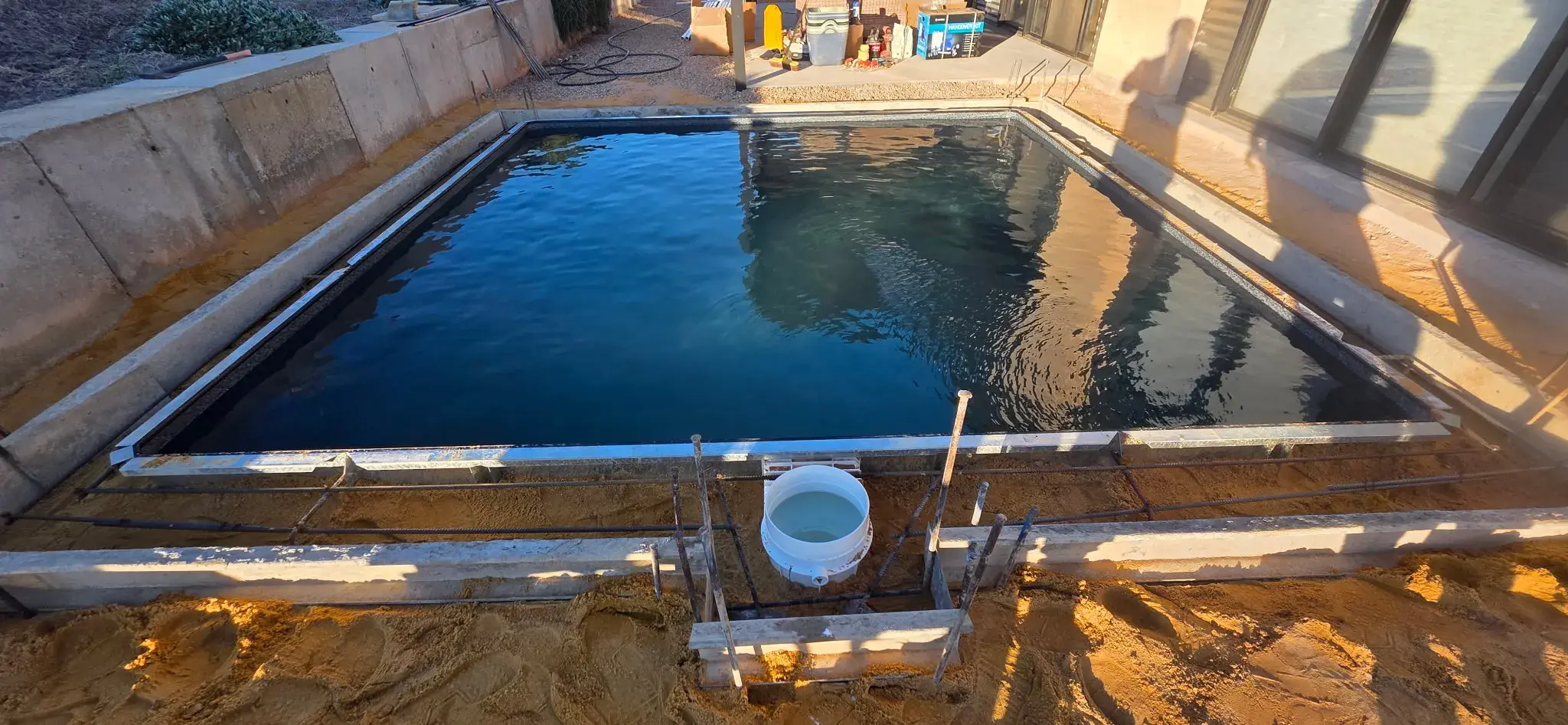 Pool filling with water showing skimmer box installation and steel frame supports