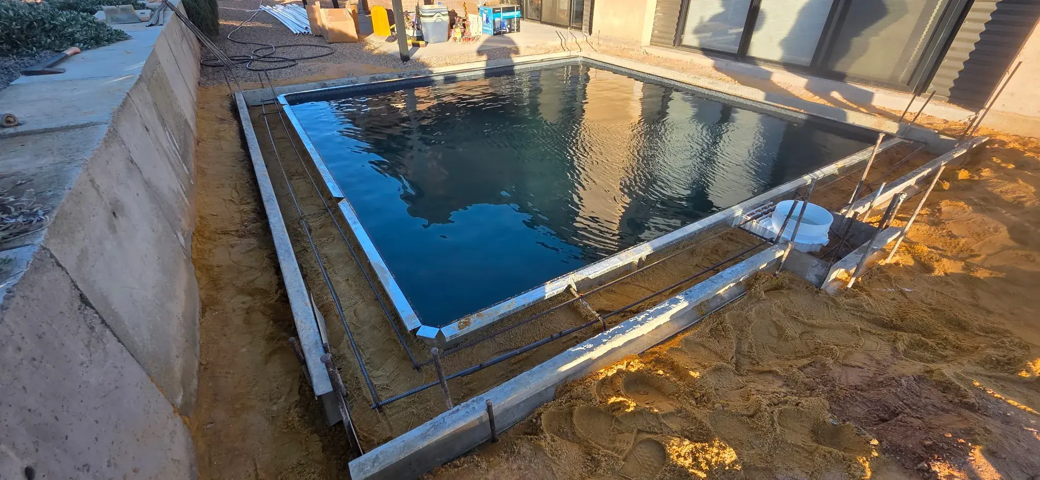 Pool filled with Antique Black liner showing dark water tone and step entry before backfill