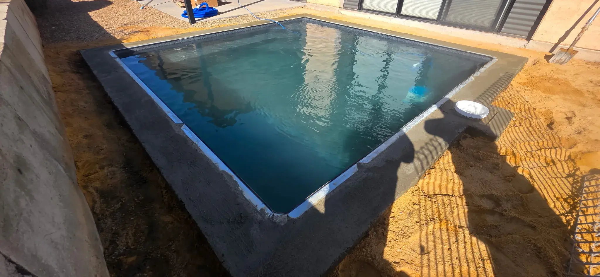 Pool filled before coping showing concrete bond beam and dark liner tone