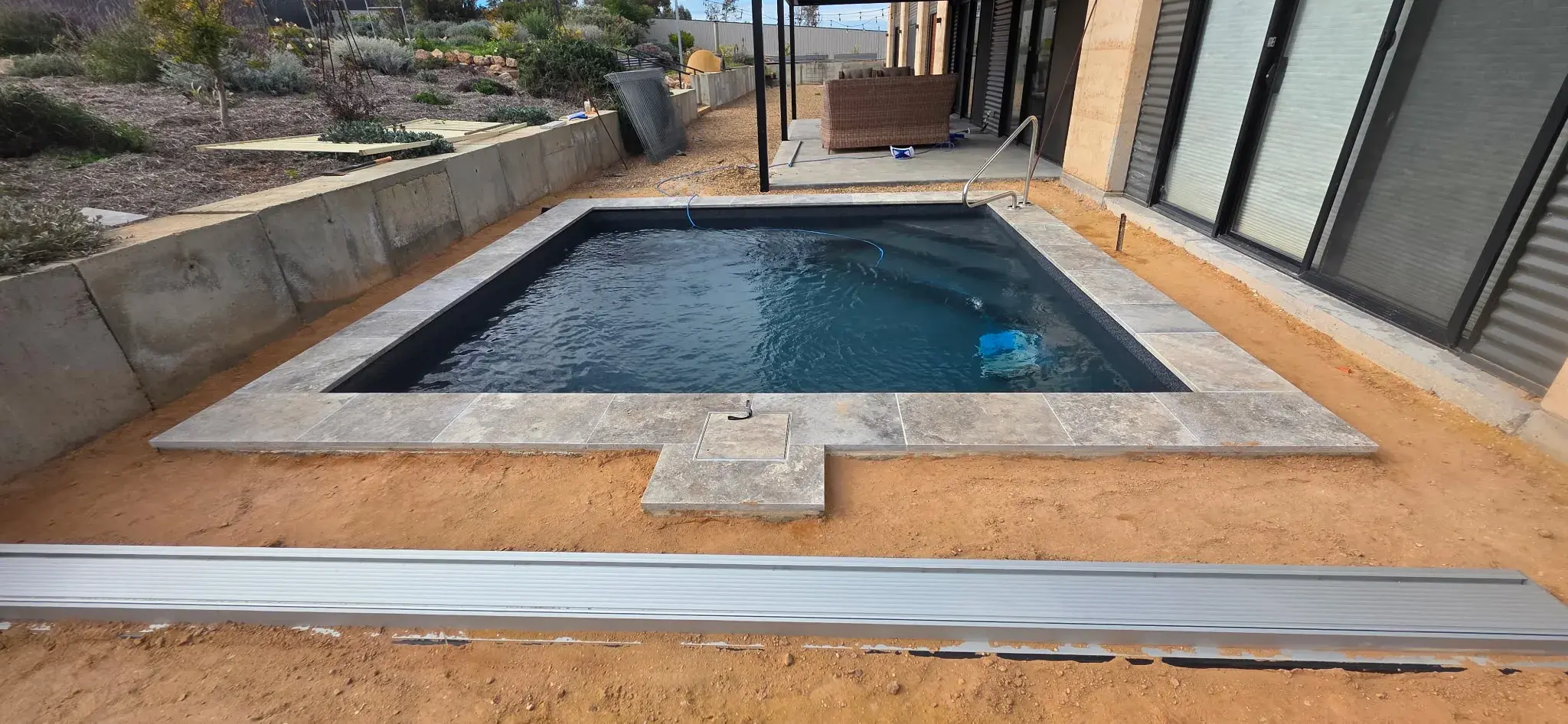Finished pool with Stonecraft Luna travertine coping, inground blanket box, and robotic cleaner