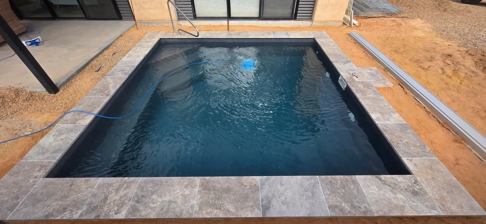 Completed 4m x 4m plunge pool with Antique Black liner, Luna travertine coping, and SR Smith handrail