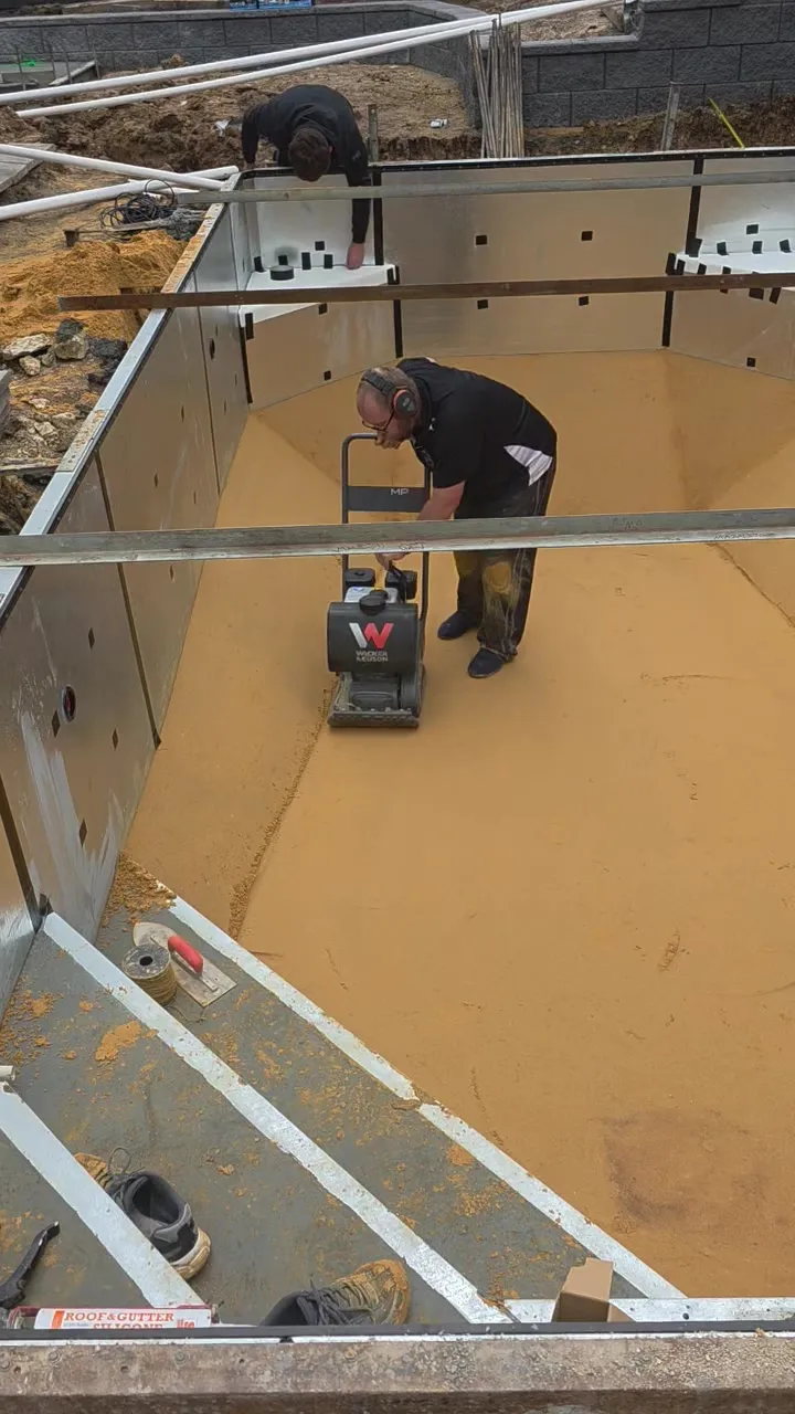 Plate compactor compacting the sand base inside the pool shell at Woodcroft