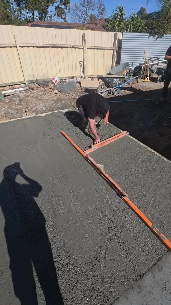 Fresh concrete surrounds being screeded beside the pool at Woodcroft